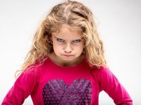 Een klein autistisch meisje kijkt heel erg boos, ze is het niet eens met haar opvoeding