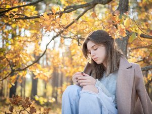 Een meisje een herfstdepressie staart somber voor zich uit in een bos in de herfst.