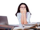 Een vrouw met examenvrees zit vol emotie angstig achter haar laptop.