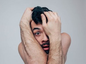 Een man met een fobie houdt zijn armen om zijn hoofd om zich te beschermen tegen de oorzaak van zijn fobie