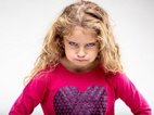 Een klein meisje kijkt heel erg boos, ze is het niet eens met haar opvoeding