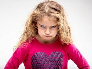 Een klein meisje kijkt heel erg boos, ze is het niet eens met haar opvoeding