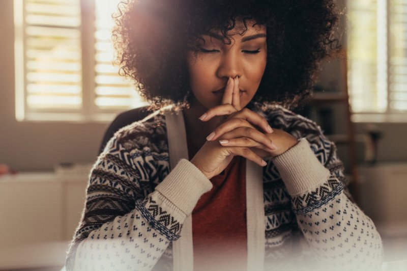 Een hoogsensitieve vrouw zit na te denken over hooggevoeligheid en hoogsensitiviteit, met haar ogen dicht. 