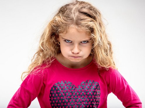Een klein meisje kijkt heel erg boos, ze is het niet eens met haar opvoeding