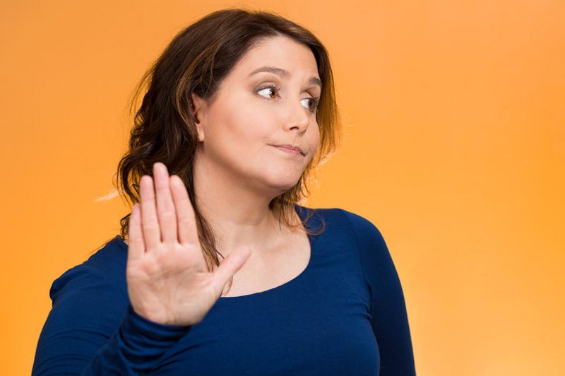Een vrouw maakt een afwerend gebaar en kijkt verwijtend de andere kant op. Met deze houding kun je ook niet verder communiceren.