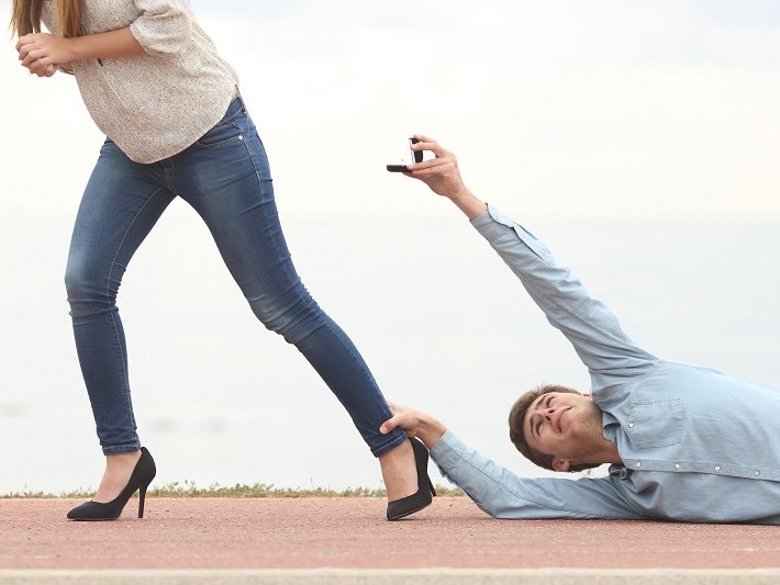 Een stel met relatieproblemen. De vrouw loopt weg maar de man sleept over de vloer, hangend aan haar enkel, terwijl hij een trouwring aan haar aanbiedt.