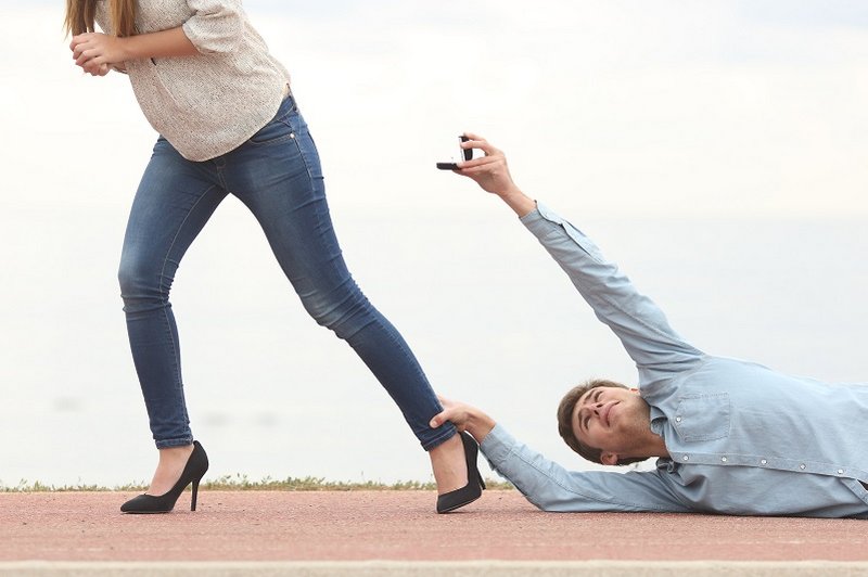 Een stel met relatieproblemen. De vrouw loopt weg maar de man sleept over de vloer, hangend aan haar enkel, terwijl hij een trouwring aan haar aanbiedt.