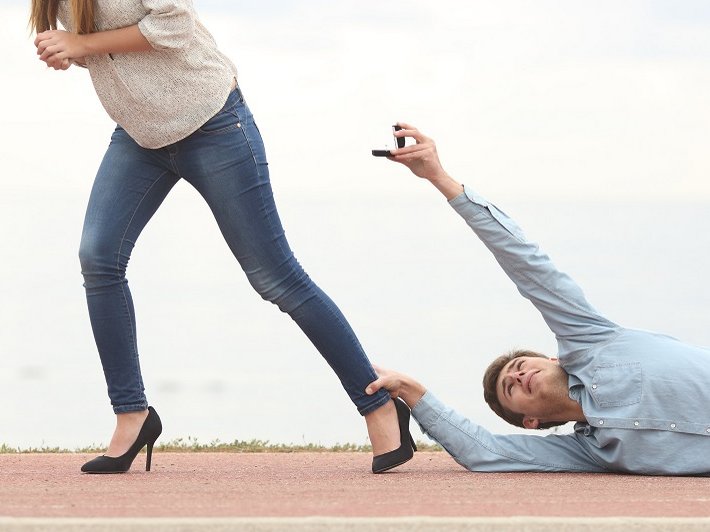 Een stel met relatieproblemen. De vrouw loopt weg maar de man sleept over de vloer, hangend aan haar enkel, terwijl hij een trouwring aan haar aanbiedt.