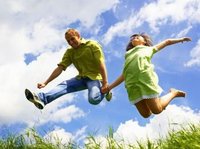 Een man en een meisje springen blij de lucht in.