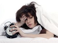 Een hooggevoelige vrouw met een burn-out wordt doodmoe wakker met een wekker in haar hand. 
