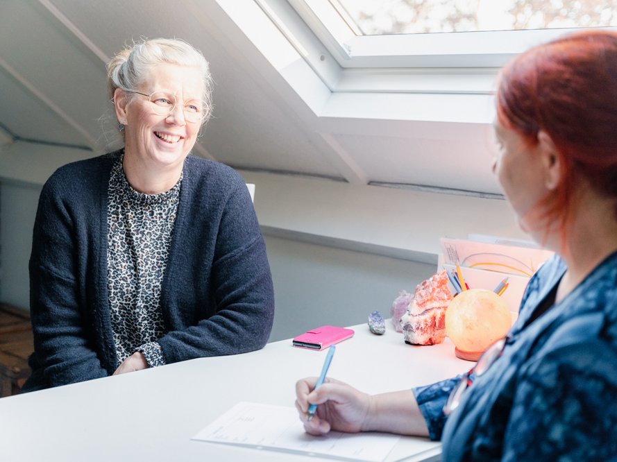 Jackelien aan het bureau met een cliënt, tijdens de intake van een consult.