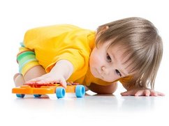 Een kleuter met autisme kijkt gefascineerd naar de wielen van zijn speelgoedauto.