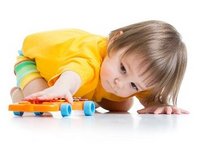 Een kleuter met autisme kijkt gefascineerd naar de wielen van zijn speelgoedauto.