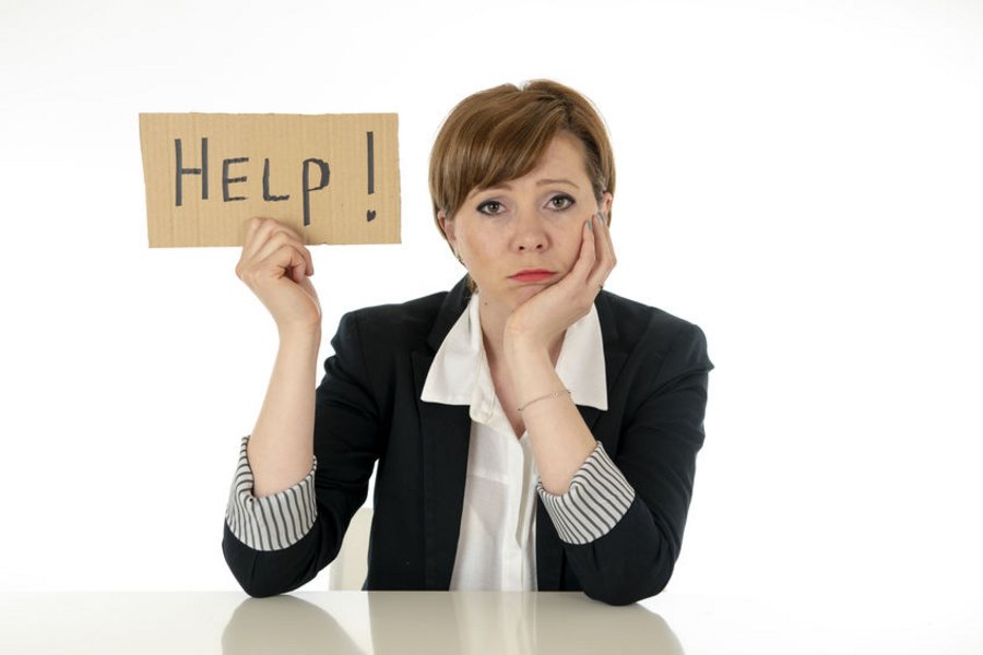Een vrouw in nette kleren kijkt bezorgd en houdt een bordje omhoog met daarop geschreven "HELP".