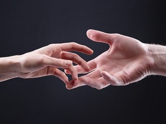 Een zwarte achtergrond met twee handen die naar elkaar reiken omdat ze hun relatie willen verbeteren.
