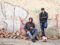 Twee pubers staan verveeld voor een muur met graffiti