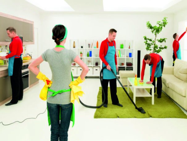 Een vrouw staat te kijken terwijl haar man op 4 plekken tegelijk de woonkamer aan het schoonmaken is.