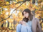 Een meisje een herfstdepressie staart somber voor zich uit in een bos in de herfst. De oorzaak van haar herfstdepressie is onzeker.