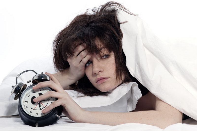 Een hooggevoelige vrouw wordt doodmoe wakker met een wekker in haar hand