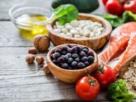 op een houten tafel ligt gezonde voeding: Zalm, note, groenten en blauwe bessen.