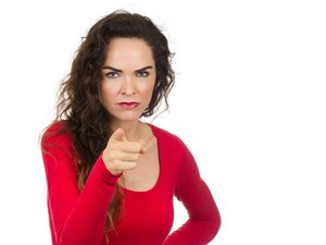 Een vrouw die boos is op haar ex, kijkt boos naar de camera, met een hand in de zij, en met de andere wijst ze naar de camera.