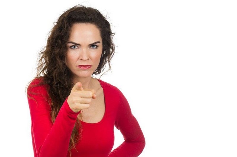 Een vrouw die boos is op haar ex, kijkt boos naar de camera, met een hand in de zij, en met de andere wijst ze naar de camera.