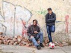 Twee vrienden met een slecht zelfbeeld staan verveeld voor een muur met graffiti