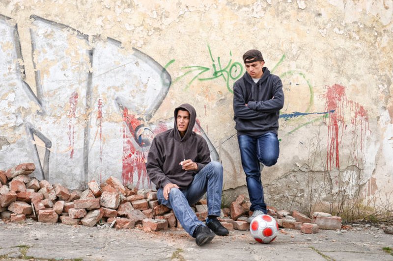 Twee pubers staan verveeld voor een muur met graffiti
