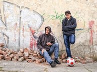 Twee pubers staan verveeld voor een muur met graffiti