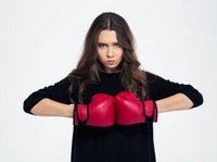 Een jonge vrouw staat klaar met rode bokshandschoenen. Soms is het moeilijk om te vergeven, als je bijvoorbeeld boos bent op je ex.