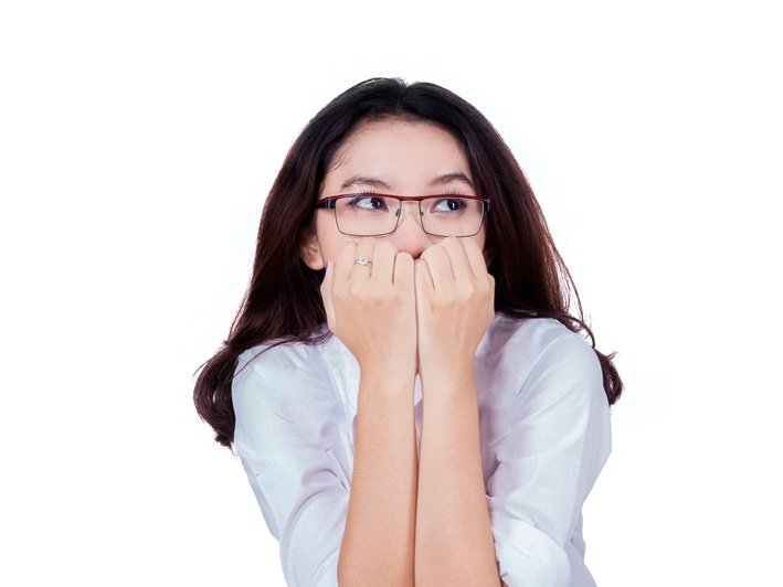 Een angstige hooggevoelige vrouw zit angstig met de vingers voor de mond tijdens een sollicitatie
