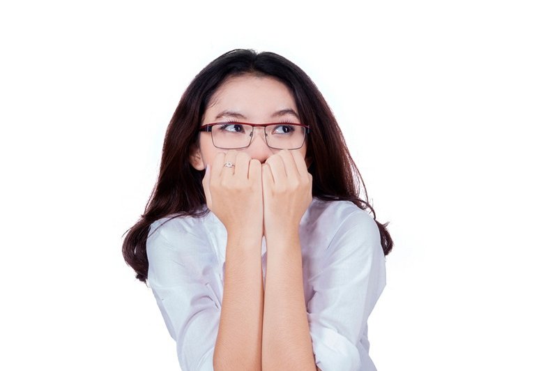 Een angstige hooggevoelige vrouw zit angstig met de vingers voor de mond tijdens een sollicitatie