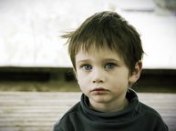 Een klein jongetje kijkt eenzaam en hulpeloos in de camera. Hij is niet jaloers, hij is ongelukkig.