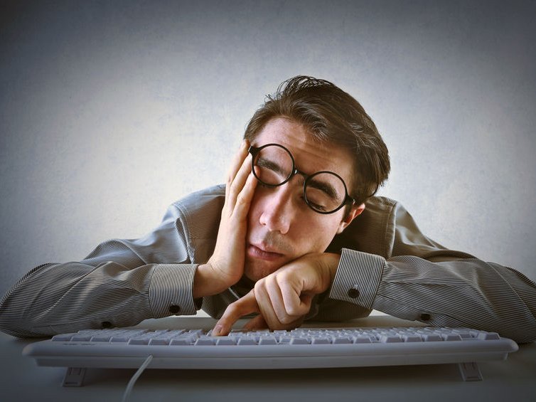 Een man hang doodmoe over zijn laptop, hij heeft energiegebrek door een blokkade in het energieveld