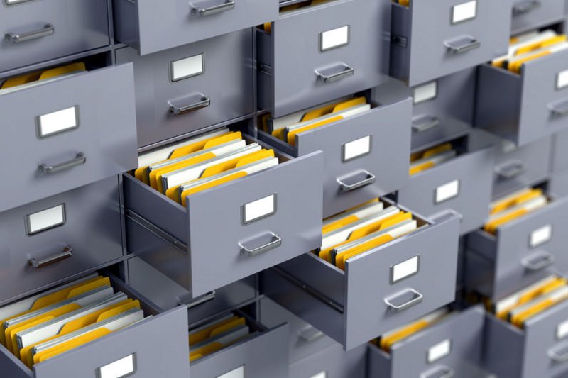 Een archiefkast vol dossiers en mappen. Alle laatjes staan open.
