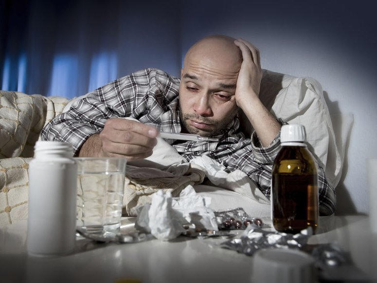 Man ligt ziek in bed met griep