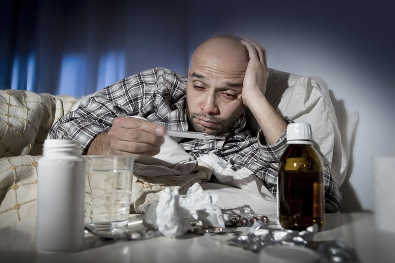 Man ligt ziek in bed met griep