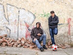 Twee pubers staan verveeld voor een muur met graffiti