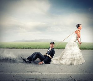 Een bruid in trouwjurk sleept haar kersverse echtgenoot over het asfalt. Zij moeten leren communiceren in hun relatie.