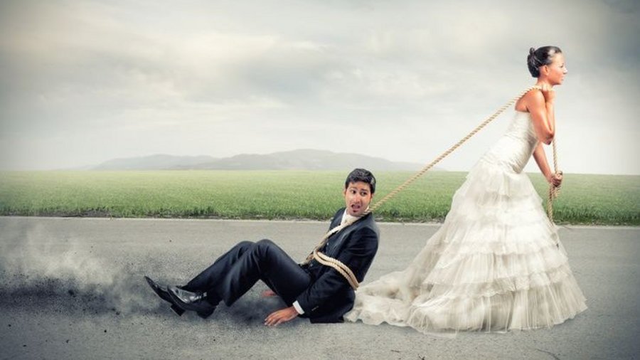 Een bruid in trouwjurk sleept haar kersverse echtgenoot over het asfalt. Zij moeten leren communiceren in hun relatie.