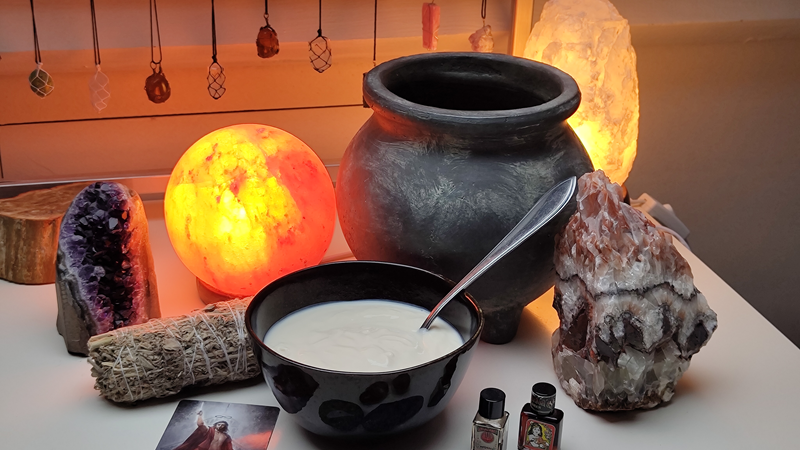 Ingrediënten voor een effectieve visualisatie: een schaaltje yoghurt temidden van edelstenen, flesjes, salie, een tarotkaart en zoutlampen