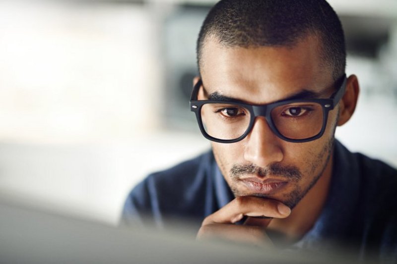 Een man kijkt met een goede concentratie naar zijn computerscherm