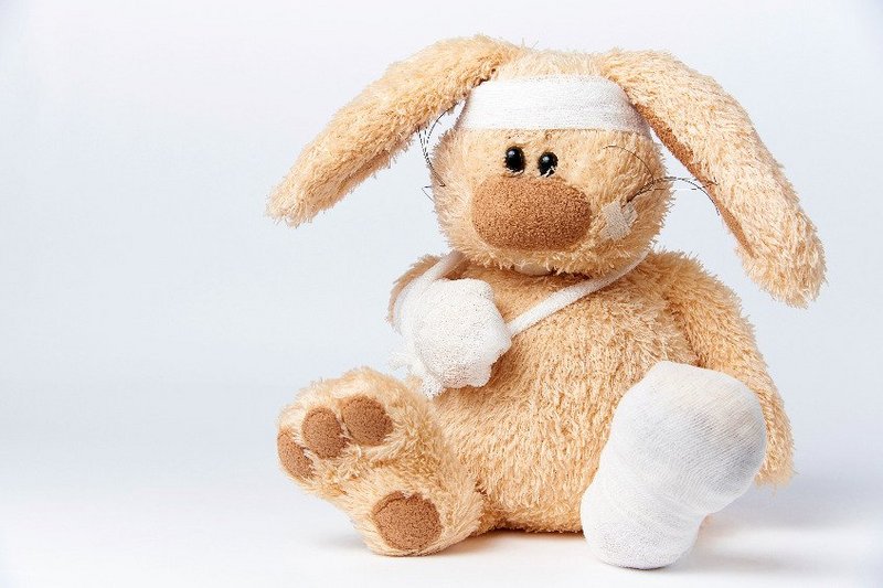 Een knuffelbeer met een jeugdtrauma zit vol pleisters en verband.