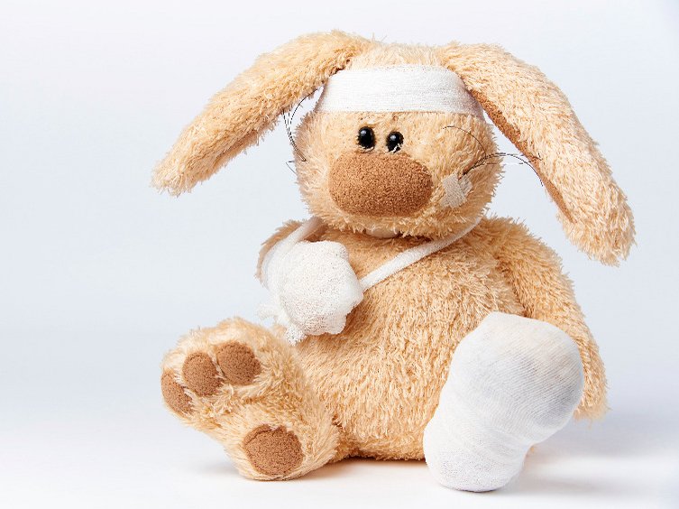 Een knuffelbeer met een jeugdtrauma zit vol pleisters en verband.
