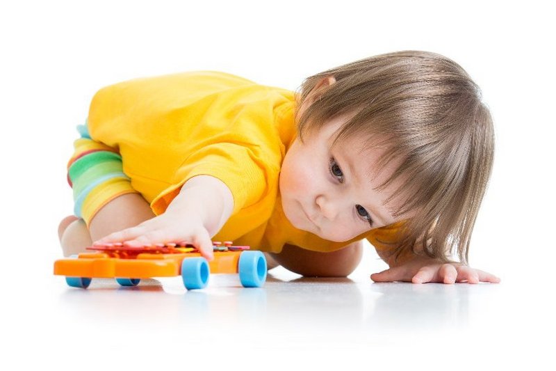 Een peuter met autisme kijkt gefascineerd aar de wielen van zijn speelgoed auto