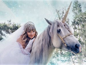 Een vrouw in bruidsjurk wacht op de ideale partner, op een witte eenhoorn, in de sneeuw. 