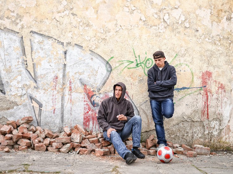 Twee pubers staan verveeld voor een muur met graffiti