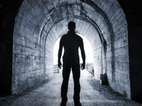 Een silhouet van een man in een tunnel. Hij heeft geen angst of uitstelgedrag, aan het eind van de tunnel is het licht.