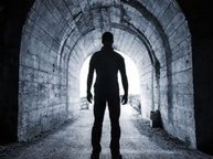 Een silhouet van een man in een tunnel. Hij heeft geen angst, aan het eind van de tunnel is het licht.