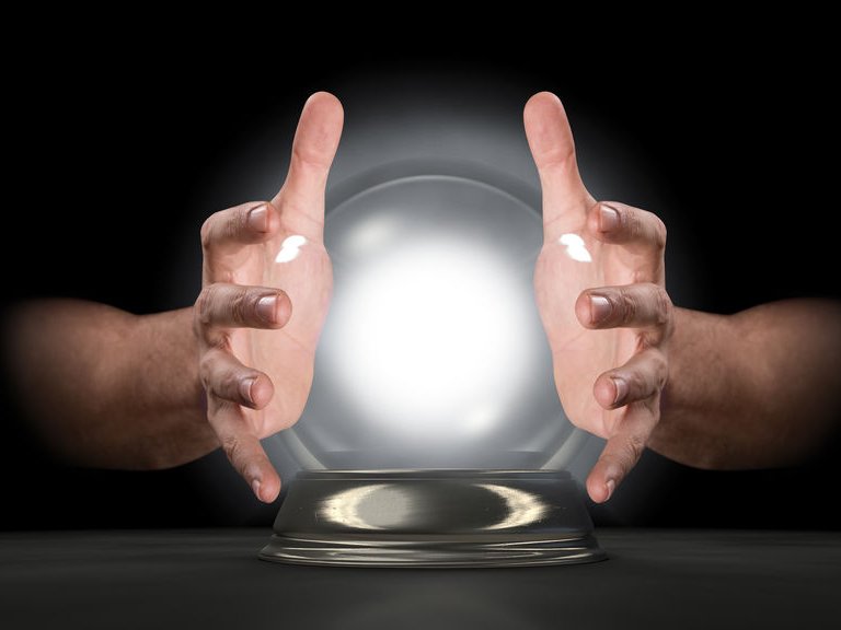 Twee handen van de paragnost, rond een glazen bol die licht geeft.